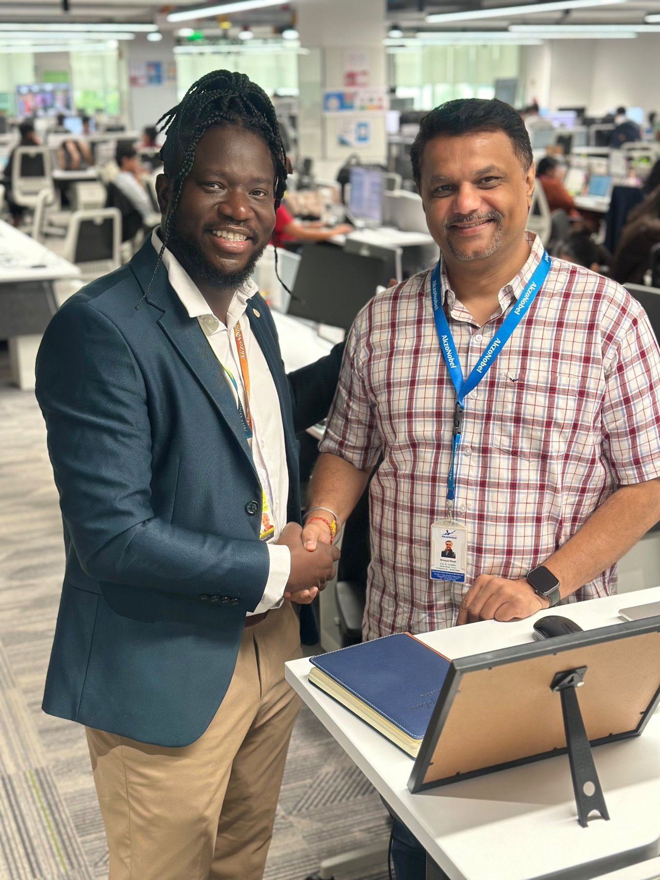 Jean Michel shaking hands with a colleague wearing an AkzoNobel lanyard in the open office